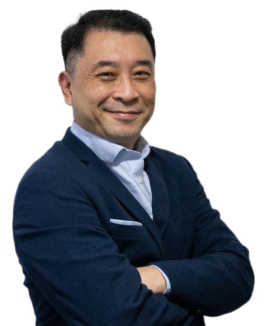 Celso Toshio Saito, de blazer azul-marinho, sorrindo de braços cruzados